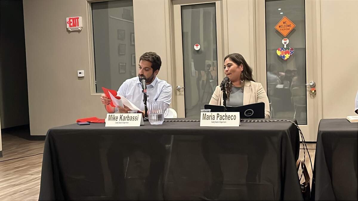 Fresno City Councilman and supervisor candidate Mike Karbassi, left, holds up a Kerman water report, during a Sept. 28, 2026, forum in northwest Fresno. Opponent, Kerman Mayor Maria Pacheco, looks on.